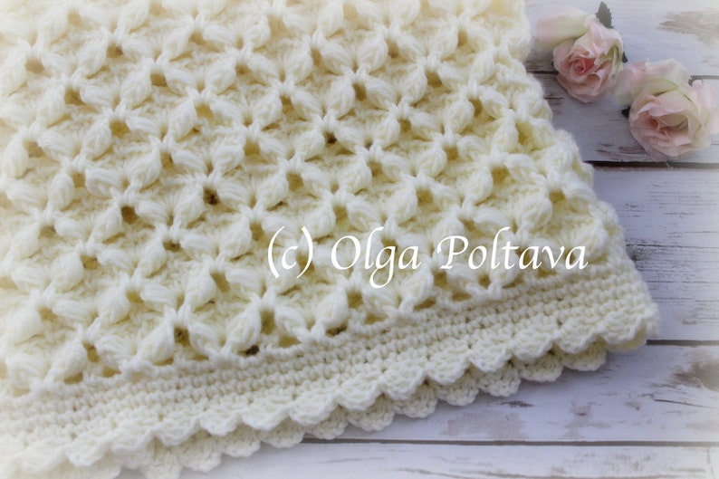 May include: A white crocheted baby blanket with a scalloped edge. The blanket is made with a delicate stitch pattern and has a soft, fluffy texture. (c) Olga Poltava