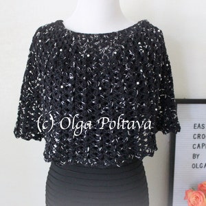 May include: Black crochet capelet with white accents and pearl embellishments. The capelet is worn over a black dress. The text "(c) Olga Poltava" is visible on the capelet.
