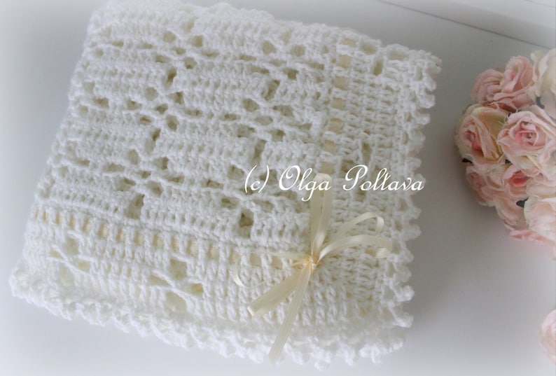 May include: White crocheted baby blanket with a delicate lace pattern and a white satin ribbon tied in a bow. (c) Olga Poltava