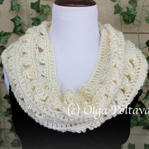 May include: A cream-colored crocheted infinity scarf featuring a textured, open-work pattern. The scarf is draped around a white mannequin neck. The text (c) Olga Poltava is visible in white lettering on the lower right side of the scarf.