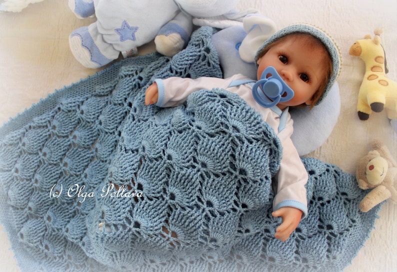 May include: A blue crocheted baby blanket with a white and blue stuffed animal and a baby doll wearing a blue hat and a dummy.