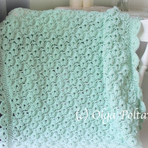 May include: A mint green crocheted blanket with a scalloped edge is draped over a white chair. The blanket features a detailed floral pattern. The image is well-lit, showcasing the texture and color of the handmade item.