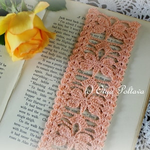 May include: A peach-coloured crocheted bookmark with a butterfly design. The bookmark is lying on a book with text. The text on the book reads "A Dream".