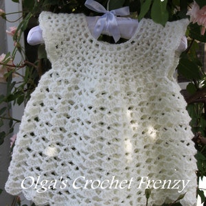 May include: White crochet baby dress with a scalloped hem. The dress is hanging on a white hanger with a white ribbon. The text "PDF Pattern Only" and "Olga's Crochet Frenzy" is visible in the image.