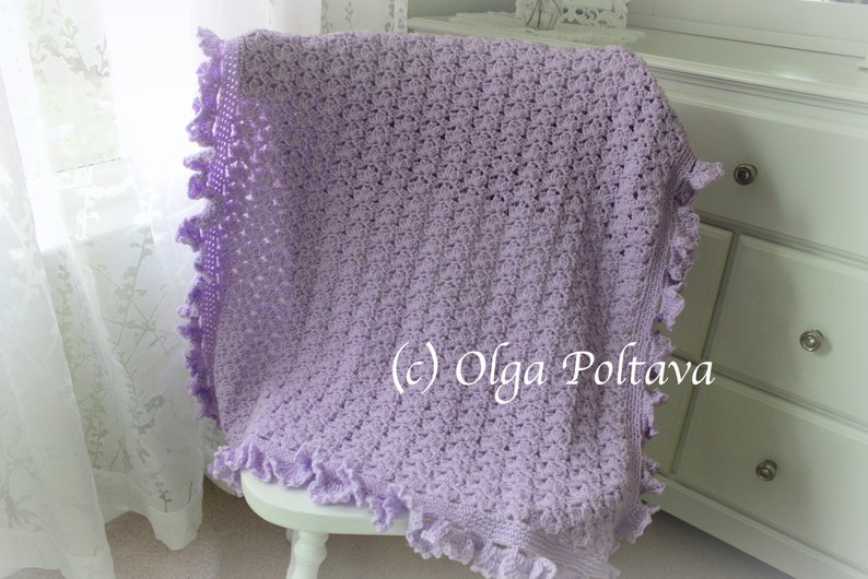 May include: A lavender crochet baby blanket with a scalloped edge. The blanket is draped over a white chair and a white dresser is in the background. (c) Olga Poltava