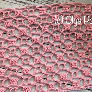 May include: A close-up of a pink crocheted fabric with a repeating openwork pattern. The delicate design features a series of connected, basket-like shapes. The text "(c) Olga Poltava" is visible in the upper right corner. The fabric is on a light wood surface.