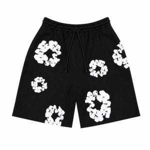 Könnte beinhalten: Schwarze Shorts mit einem weißen, abstrakten Blumen- oder Kreismuster, das auf den Stoff gedruckt ist. Die Shorts verfügen über einen elastischen Bund mit einem passenden schwarzen Kordelzug, der für einen sicheren Sitz sorgt.