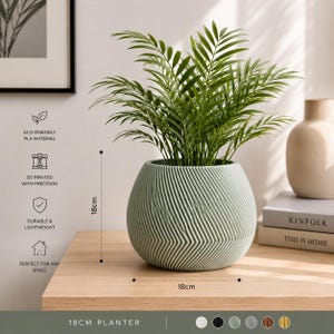 Op de afbeelding: Een saliegroene, bolvormige plantenbak met een getextureerd, diagonaal ribbelpatroon. De plantenbak meet 18 cm in hoogte en 18 cm in breedte. Het bevat een groene palmplant. Tekst op de afbeelding: ECO-FRIENDLY PLA MATERIAL, 3D PRINTED WITH PRECISION, DURABLE & LIGHTWEIGHT, PERFECT FOR ANY SPACE, 18CM PLANTER.
