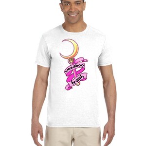May include: White t-shirt with a pink and gold graphic of a crescent moon and a wand with the text "weeaboo trash" on a pink ribbon.