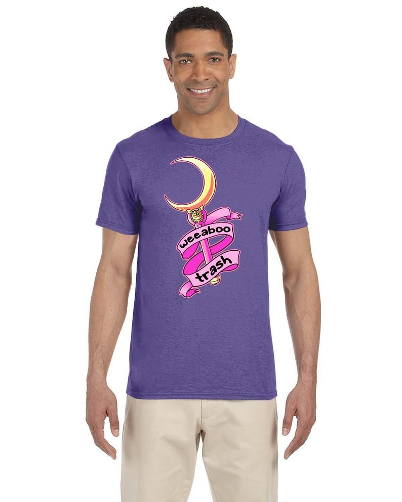 May include: A purple t-shirt with a pink and gold cartoon image of a crescent moon and wand with the text "weeboo trash" on a pink ribbon.