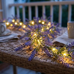 May include: A string of artificial lavender flowers intertwined with small, warm white LED fairy lights. The purple floral stems and green leaves are arranged in a decorative garland, with the glowing lights nestled among the petals.