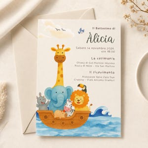 May include: A baptism invitation card featuring a watercolor illustration of a brown wooden boat on blue water carrying a giraffe, elephant, hippo, zebra, lion, and toucan. The text reads Il Battesimo di Alicia, Sabato 14 novembre 2026, ore 18:00.
