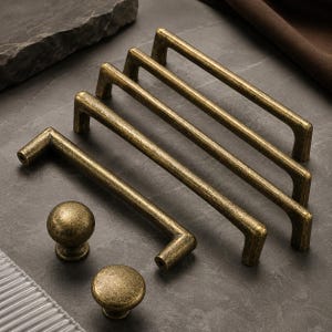 May include: A collection of antique brass hardware featuring three elongated rectangular drawer pulls with straight bars and two matching spherical cabinet knobs. Each piece displays a weathered, textured metallic finish with dark highlights.