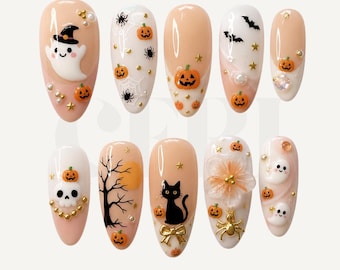 Może przedstawiać: Zestaw dziesięciu migdałowych sztucznych paznokci z motywami halloweenowymi, takimi jak duszki, dynie, czarne koty, pająki, pajęczyny, nietoperze i czaszka, ozdobione złotymi gwiazdkami, perełkami oraz złotą kokardką.