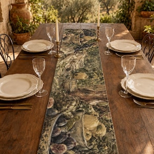 May include: A rectangular table runner featuring a detailed botanical print of various fruits and vegetables, including artichokes, figs, and pears, in muted earth tones. The runner is centred on a long wooden table with white plates and glasses.