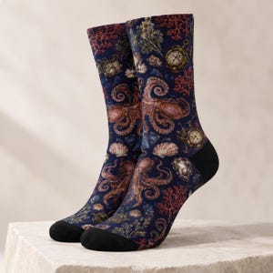 May include: A pair of crew socks featuring a dark blue background with a repeating pattern of brown octopuses, red coral, seashells, and vintage gold pocket watches. The socks have solid black toe and heel sections for a contrasting finish.