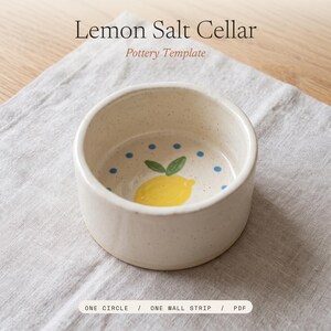 May include: A round, off-white speckled ceramic salt cellar featuring a hand-painted yellow lemon with green leaves at the center and blue dots around the interior. The text reads Lemon Salt Cellar Pottery Template One Circle / One Wall Strip / PDF.