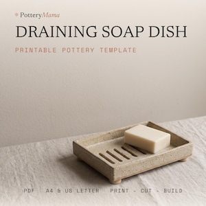 Puede incluir: Una jabonera rectangular de cerámica beige moteada con ranuras de drenaje y cuatro patas pequeñas, que sostiene una pastilla de jabón blanca rectangular. El texto dice PotteryMama DRAINING SOAP DISH PRINTABLE POTTERY TEMPLATE PDF A4 & US LETTER PRINT - CUT - BUILD.