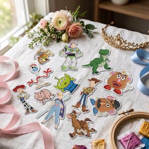 May include: A collection of twelve embroidered patches featuring various animated characters including a space ranger, a green dinosaur, a cowboy, a cowgirl, a fork-shaped toy, a three-eyed alien, a pig, a horse, and two potato-shaped figures.