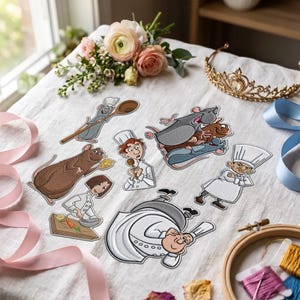 May include: A collection of embroidered patches featuring cartoon characters including rats, chefs, and culinary scenes. The patches are arranged on a white fabric surface alongside a gold tiara, pink ribbons, and a bouquet of pink and white flowers.