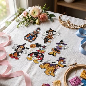 May include: A collection of six die-cut stickers featuring cartoon characters dressed in Halloween costumes, including a vampire, a witch, and a ghost. The stickers display vibrant colors and detailed outlines of various iconic animated figures.