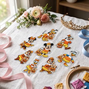 May include: A collection of eight embroidered patches featuring Disney characters dressed in candy corn-themed outfits, each holding a paper bag with a pumpkin graphic and the text Trick or Treat, arranged on a white fabric surface.