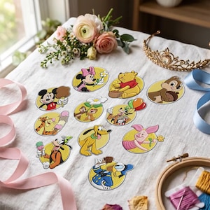 Può includere: Una collezione di undici toppe in tessuto ricamato raffiguranti vari personaggi Disney, tra cui Topolino, Minni, Winnie the Pooh, Tigro, Pimpi, Pippo, Pluto, Paperino e Cip e Ciop, disposte su una superficie di tessuto di lino bianco.