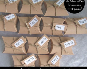 May include: Twelve brown paper boxes with twine and handwritten labels numbered 1 through 12. The boxes are arranged in rows and are part of a Yule Witchy Advent Calendar. The text "Please note, the labels will be hand-written NOT printed" is visible in the image.