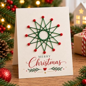 Puede incluir: Una tarjeta de felicitación de color crema con un diseño de arte en hilo en forma de estrella hecho con hilo verde y pequeñas cuentas rojas. Debajo del diseño, el texto Merry Christmas está impreso en rojo y negro, junto a un corazón rojo y ramas.