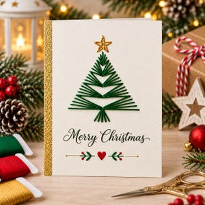 Könnte beinhalten: Eine weiße Grußkarte mit einem gestickten grünen Weihnachtsbaum und einem goldenen Stern an der Spitze. Der Text Merry Christmas ist in Schwarz unter dem Baum gedruckt, ergänzt durch ein kleines rotes Herz und grüne Zweigakzente.