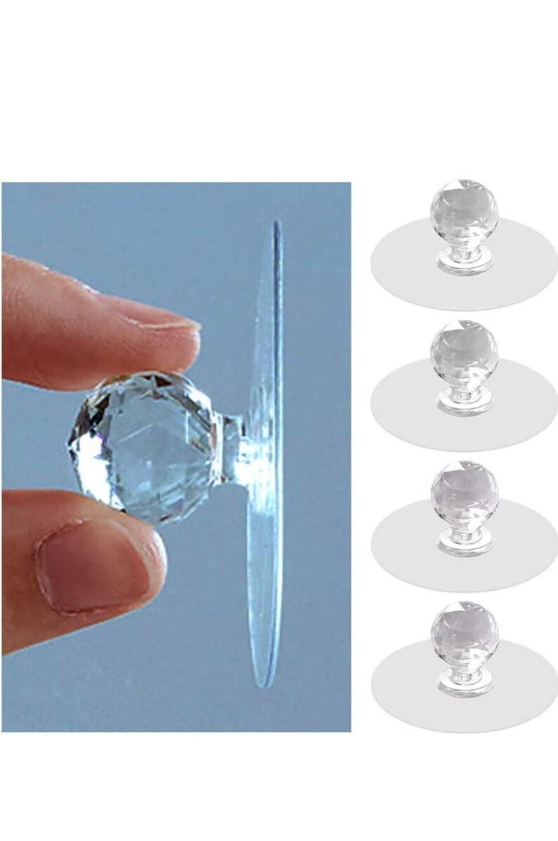 May include: A set of four clear, faceted, spherical knobs, each attached to a flat, circular, transparent adhesive base. The knobs feature a multi-faceted surface that reflects light, and the design includes a clear, round backing for mounting.