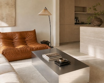 Mesa de centro em alumínio brilhante com base minimalista prateada para sala de estar moderna.