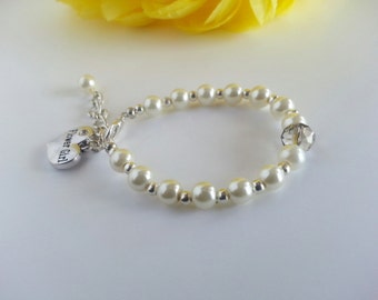 Könnte beinhalten: Ein weißes Perlenarmband mit einem silbernen Anhänger, auf dem "Flower Girl" steht, und einer klaren Kristallperle.