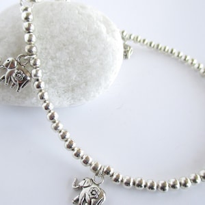 May include: Silver anklet with small elephant charms. The anklet is made of tiny silver beads and has four elephant charms.
