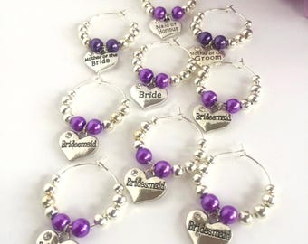 Könnte beinhalten: Set aus 8 silbernen und violetten Glasanhängern mit herzförmigen Etiketten. Die Etiketten tragen die Aufschriften "Maid of Honor", "Mother of the Bride", "Mother of the Groom", "Bride" und "Bridesmaid".
