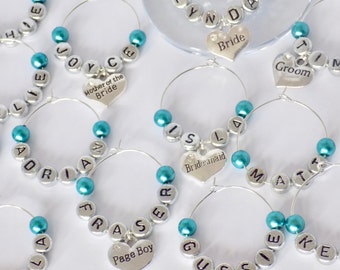 Könnte beinhalten: Set aus 10 personalisierten Weinglasanhängern in Türkis und Silber mit herzförmigen Anhängern, auf denen "Bride", "Groom", "Mother of the Bride", "Bridesmaid", "Page Boy", "John", "Joyce", "Adrian", "Fraser", "Isabella", "Lynda", "Matt", "Gus", "Ellie", "Tim" und "Isla" steht.