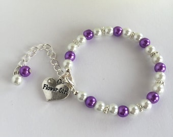 Könnte beinhalten: Ein Armband aus weißen und lila Perlen mit einem silbernen Herzanhänger, auf dem "Flower Girl" steht.