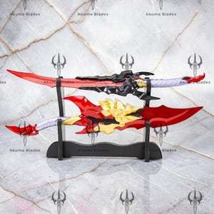May include: Two fantasy swords displayed on a black stand. The top sword has a red blade, black hilt, and silver handle. The bottom sword features a red blade, gold guard, and silver handle. The text Akuma Blades is repeated across the image.