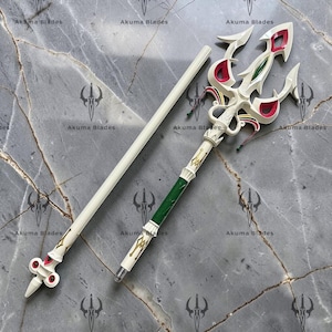 May include: A two-piece white trident staff featuring a three-pronged head with red and green accents. The shaft includes a green grip section, gold decorative detailing, and small colorful tassels attached near the base of the trident head.