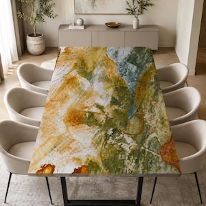 May include: A rectangular dining table featuring a polished stone surface with swirling patterns of amber, forest green, and white. The table is supported by a black metal frame and is surrounded by six cream-colored upholstered chairs.