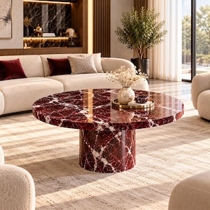 Op de afbeelding: Een ronde salontafel met een dieprood en wit marmeren oppervlak met een gepolijste afwerking. De tafel wordt ondersteund door een cilindrische voet van hetzelfde rood-witte marmermateriaal, wat zorgt voor een samenhangend geheel.