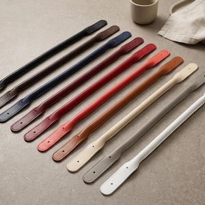Puede incluir: Una colecci&oacute;n de nueve asas de bolso largas y delgadas dispuestas en diagonal en una fila. Las asas est&aacute;n disponibles en una variedad de colores que incluyen negro, marr&oacute;n oscuro, azul marino, granate, rojo, tostado, crema, gris y blanco.