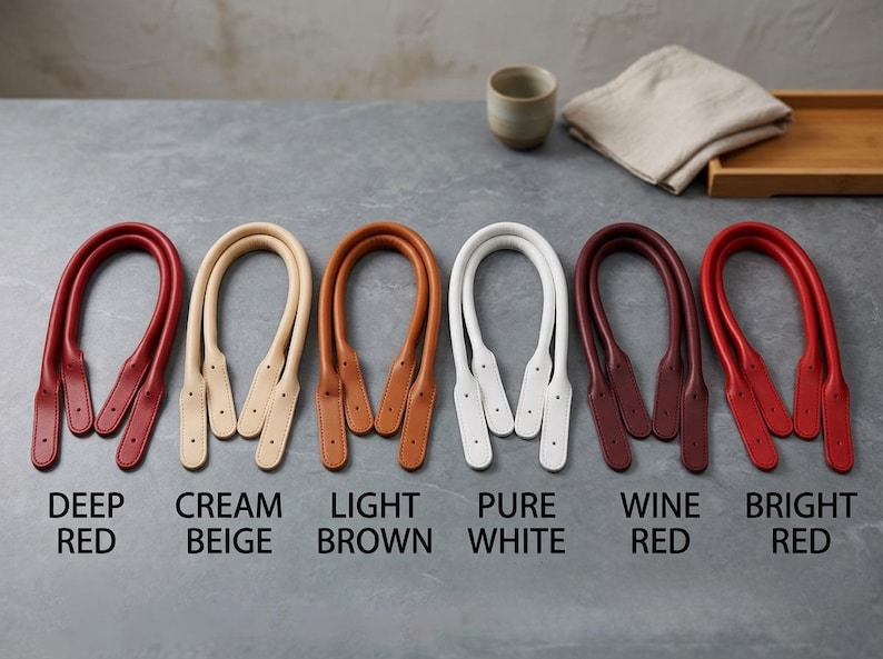 Puede incluir: Seis pares de asas para bolso en forma de U en varios colores, etiquetadas como Deep Red, Cream Beige, Light Brown, Pure White, Wine Red y Bright Red. Cada par presenta extremos cosidos con agujeros preperforados para fijar al bolso.