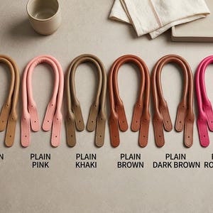 Puede incluir: Seis pares de asas para bolso en forma de U de varios colores, etiquetadas como Plain Tan, Plain Pink, Plain Khaki, Plain Brown, Plain Dark Brown y Plain Rose Pink. Cada par cuenta con un agarre redondeado y acolchado y extremos planos.