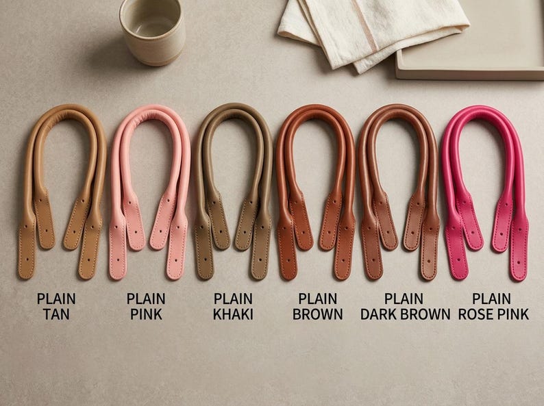 Puede incluir: Seis pares de asas para bolso en forma de U de varios colores, etiquetadas como Plain Tan, Plain Pink, Plain Khaki, Plain Brown, Plain Dark Brown y Plain Rose Pink. Cada par cuenta con un agarre redondeado y acolchado y extremos planos.