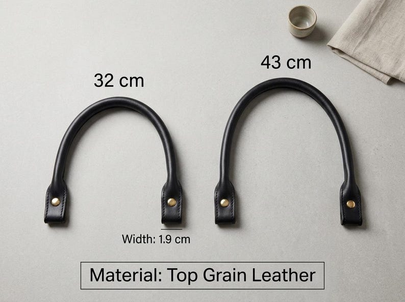 Puede incluir: Dos asas de bolso de cuero de grano superior en color negro con remaches met&aacute;licos dorados. Un asa mide 32 cm y la otra 43 cm de largo. Ambas asas tienen un ancho de 1,9 cm. El texto en la imagen indica que el material es cuero de grano superior.