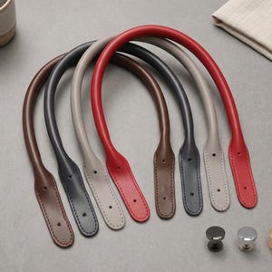 Puede incluir: Cuatro asas de bolso arqueadas en marr&oacute;n, gris oscuro, gris claro y rojo, cada una con extremos cosidos con dos orificios preperforados para su fijaci&oacute;n. Tres peque&ntilde;os cierres met&aacute;licos redondos en negro, plata y oro se sit&uacute;an debajo.