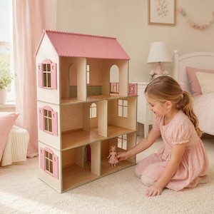 Può includere: Una casa delle bambole in legno a tre piani con tetto a capanna rosa, pareti chiare e persiane rosa. La struttura comprende diverse stanze aperte con motivi sulle pareti, un piccolo balcone all'ultimo piano e una piccola bambola.