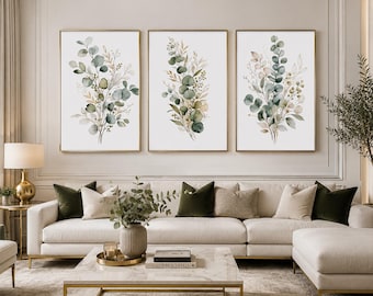 May include: A set of three vertical wall art prints featuring watercolor illustrations of eucalyptus branches and foliage in shades of sage green, muted olive, and soft beige, each enclosed in a thin gold frame and displayed on a white wall.