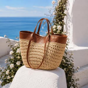 May include: A tote bag featuring a tan woven straw body with a wide, smooth brown leather upper section and two matching brown leather shoulder straps. The transition between the straw and leather is finished with a decorative scalloped edge.